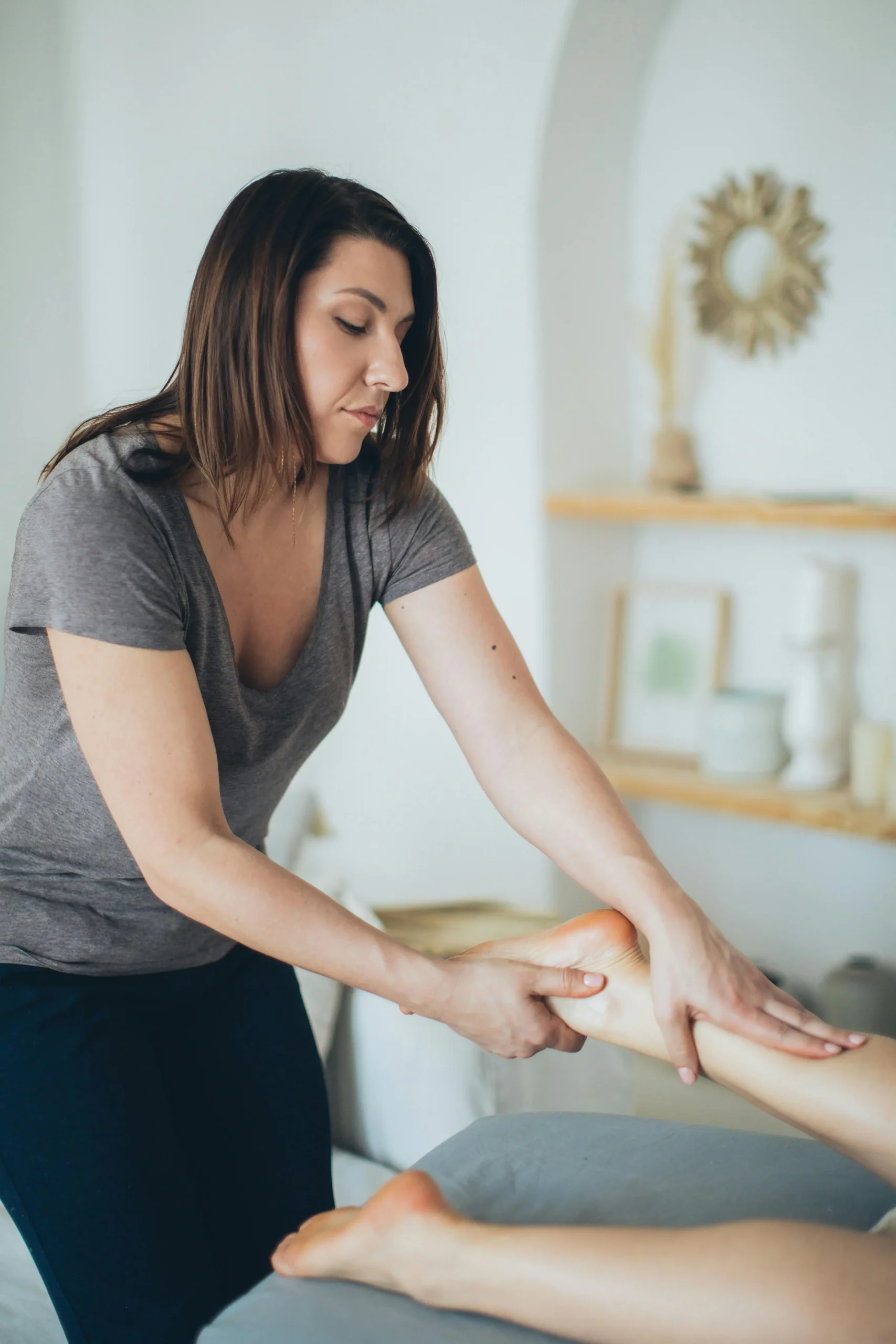 Portrait d’une réflexologue pratiquant une séance de réflexologie plantaire sur une cliente.